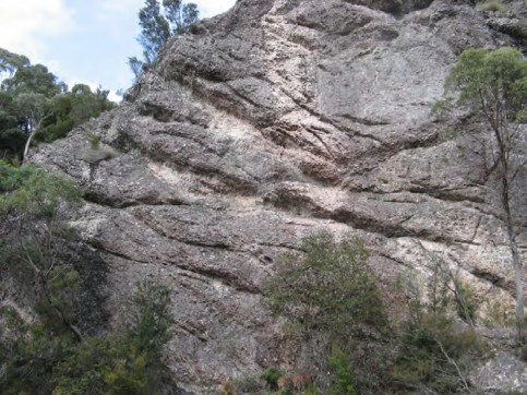 A rocky mountain with trees in the background Description automatically generated